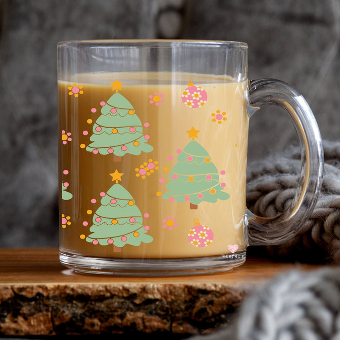 a glass mug of coffee with christmas trees on it